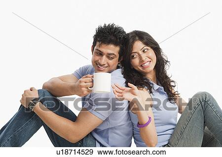 Man drinking coffee and sitting with his girlfriend View Large Photo Image Stock Photo - Man drinking coffee and sitting with his girlfriend. Fotosearch
