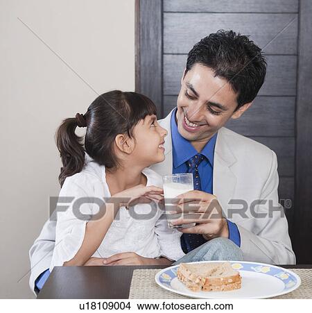 Picture - Man feeding milk to his daughter. Fotosearch