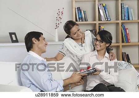 Stock Photo - Man gifting a laptop to his daughter. Fotosearch