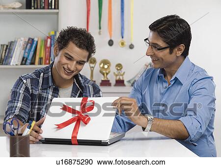 Man gifting a laptop to his son View Large Photo Image Stock Image - Man gifting a laptop to his son. Fotosearch