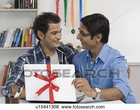 Man gifting a laptop to his son View Large Photo Image Stock Photo - Man gifting a laptop to his son. Fotosearch