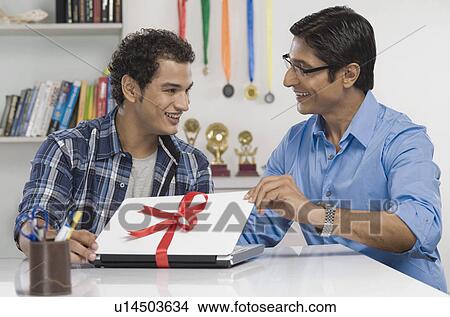 Man giving a laptop in gift to his son View Large Photo Image Picture - Man giving a laptop in gift to his son. Fotosearch