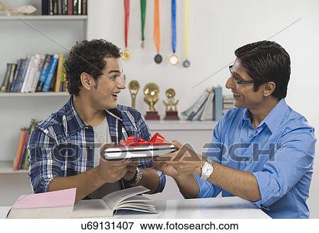 Man giving a laptop in gift to his son View Large Photo Image Stock Photo - Man giving a laptop in gift to his son. Fotosearch