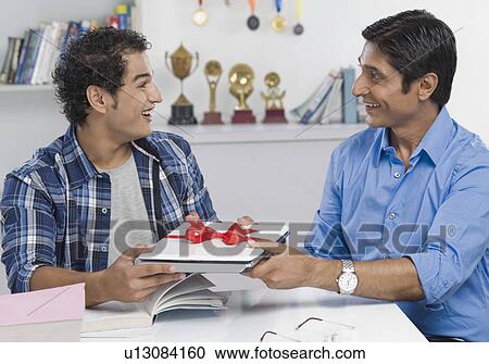 Man giving a laptop to his son View Large Photo Image Stock Image - Man giving a laptop to his son. Fotosearch