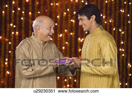 Man giving Diwali gift to his father View Large Photo Image Stock Image - Man giving Diwali gift to his father. Fotosearch