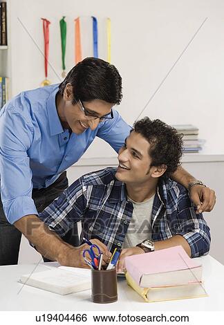 Man helping his son in study View Large Photo Image Stock Photograph - Man helping his son in study. Fotosearch