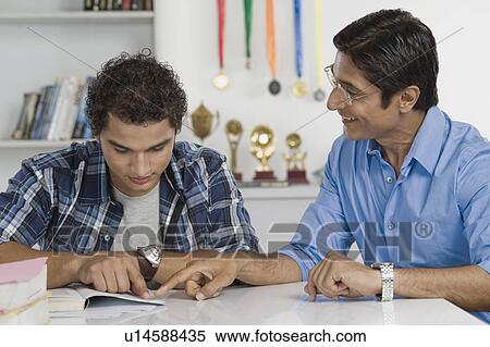 Stock Photography - Man helping his son in study. Fotosearch