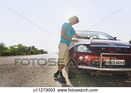 Man holding a map on a car hood View Large Photo Image Stock Image - Man holding a map on a car hood. Fotosearch