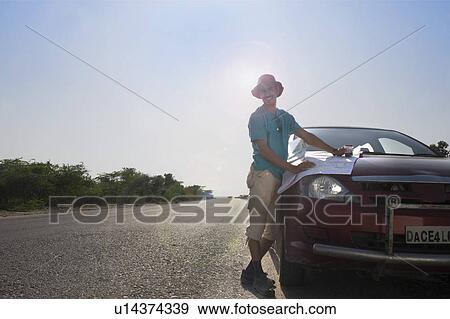 Stock Photo - Man holding a map on a car hood. Fotosearch