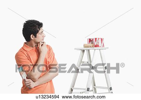 Picture - Man holding a paintbrush and thinking. Fotosearch