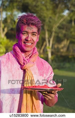 Stock Image - Man holding a plate of powder paint on Holi. Fotosearch