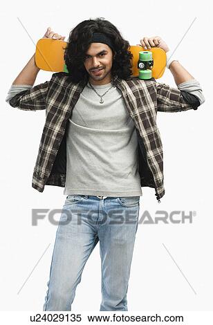 Stock Photography - Man holding a skateboard on his shoulders. Fotosearch