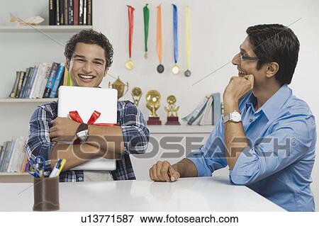 Man hugging a laptop gifted by his father View Large Photo Image Stock Photo - Man hugging a laptop gifted by his father. Fotosearch