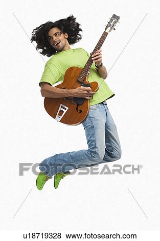 Man jumping in the air while playing a guitar View Large Photo Image Stock Photo - Man jumping in the air while playing a guitar. Fotosearch