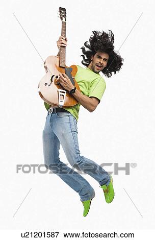 Man jumping in the air while playing a guitar View Large Photo Image Stock Photo - Man jumping in the air while playing a guitar. Fotosearch