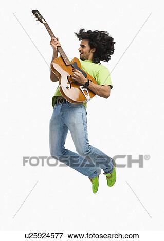 Man jumping in the air while playing a guitar View Large Photo Image Stock Photo - Man jumping in the air while playing a guitar. Fotosearch