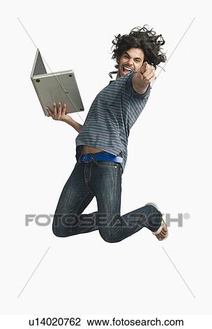 Stock Image - Man jumping while using a laptop. Fotosearch