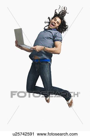 Man jumping while using a laptop View Large Photo Image Stock Image - Man jumping while using a laptop. Fotosearch