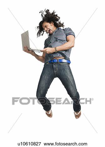 Stock Photo - Man jumping while using a laptop. Fotosearch
