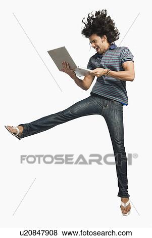 Man jumping while using a laptop View Large Photo Image Stock Photo - Man jumping while using a laptop. Fotosearch
