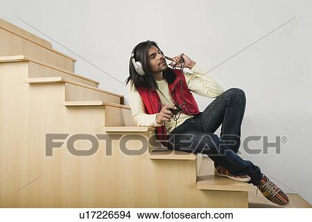 Man listening to an MP3 player on a staircase View Large Photo Image Picture - Man listening to an MP3 player on a staircase. Fotosearch