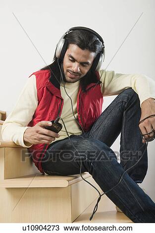 Man listening to an MP3 player on a staircase View Large Photo Image Stock Image - Man listening to an MP3 player on a staircase. Fotosearch