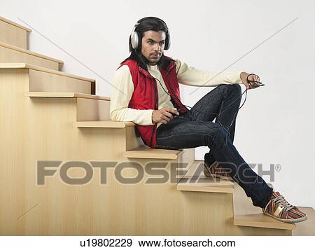 Man listening to an MP3 player on a staircase View Large Photo Image Stock Photo - Man listening to an MP3 player on a staircase. Fotosearch