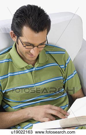Man reading a book in an armchair View Large Photo Image Stock Image - Man reading a book in an armchair. Fotosearch