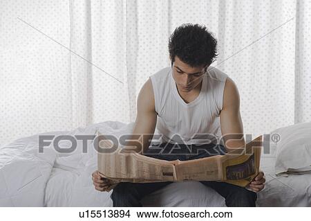 Man reading a newspaper on the bed View Large Photo Image Picture - Man reading a newspaper on the bed. Fotosearch