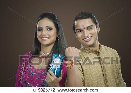 Stock Image - Man showing his rakhi with his sister showing her present. Fotosearch