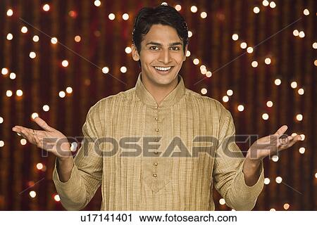 Stock Image - Man shrugging in front of Diwali decoration. Fotosearch