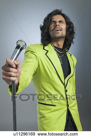 Man singing into a microphone View Large Photo Image Stock Photo - Man singing into a microphone. Fotosearch