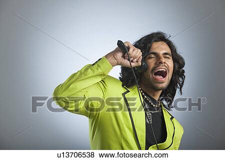 Man singing into a microphone View Large Photo Image Stock Photo - Man singing into a microphone. Fotosearch
