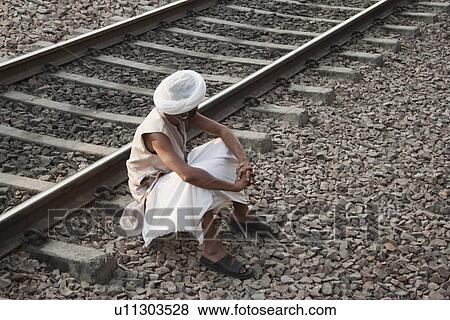 Stock Photo - Man sitting near railroad track, Ahmedabad, Gujarat, India. Fotosearch