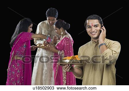 Man talking on a mobile phone with his family in the background View Large Photo Image Stock Image - Man talking on a mobile phone with his family in the background. Fotosearch