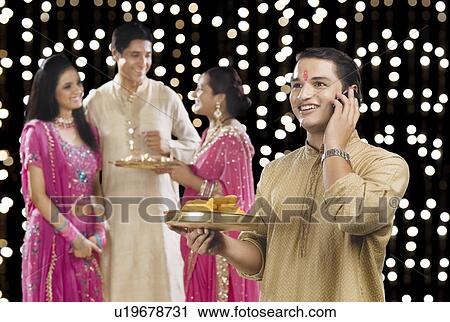 Man talking on a mobile phone with his family in the background View Large Photo Image Stock Image - Man talking on a mobile phone with his family in the background. Fotosearch