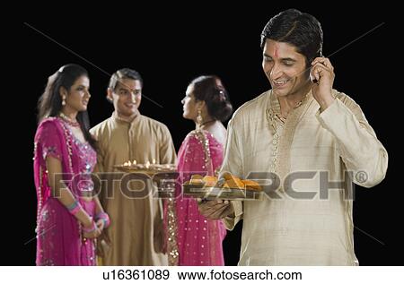 Man talking on a mobile phone with his family in the background View Large Photo Image Stock Photo - Man talking on a mobile phone with his family in the background. Fotosearch