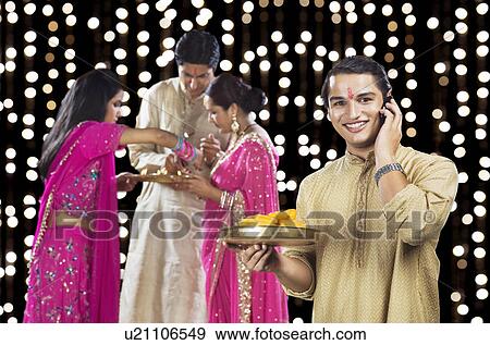Man talking on a mobile phone with his family in the background View Large Photo Image Stock Photo - Man talking on a mobile phone with his family in the background. Fotosearch