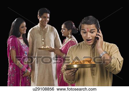 Man talking on a mobile phone with his family in the background View Large Photo Image Stock Photograph - Man talking on a mobile phone with his family in the background. Fotosearch