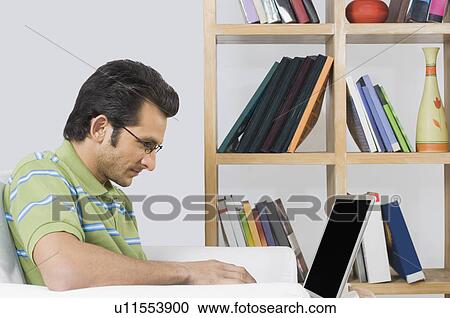 Stock Image - Man using a laptop in an armchair. Fotosearch