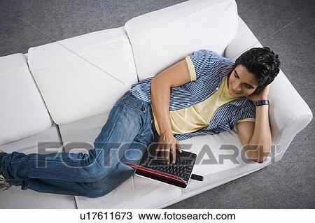 Man using a laptop on a couch View Large Photo Image Stock Image - Man using a laptop on a couch. Fotosearch