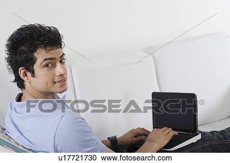 Man using a laptop on a couch View Large Photo Image Stock Image - Man using a laptop on a couch. Fotosearch