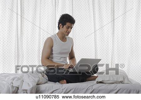 Man using a laptop on the bed View Large Photo Image Stock Photography - Man using a laptop on the bed. Fotosearch