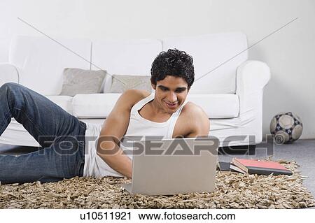 Man using a laptop on the floor View Large Photo Image Stock Image - Man using a laptop on the floor. Fotosearch