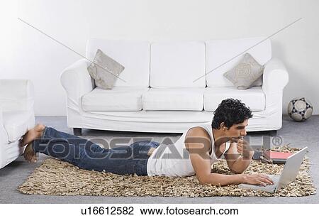 Stock Image - Man using a laptop on the floor. Fotosearch