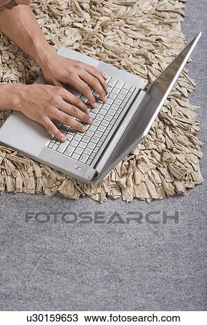 Stock Image - Man using a laptop on the floor. Fotosearch