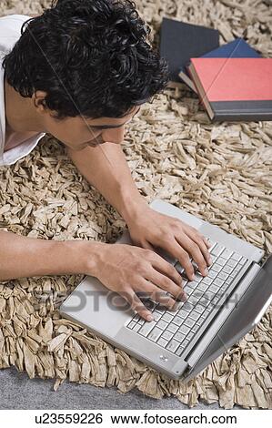 Stock Photograph - Man using a laptop on the floor. Fotosearch