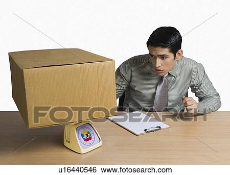 Man weighing a cardboard box and recording data View Large Photo Image Stock Photograph - Man weighing a cardboard box and recording data. Fotosearch