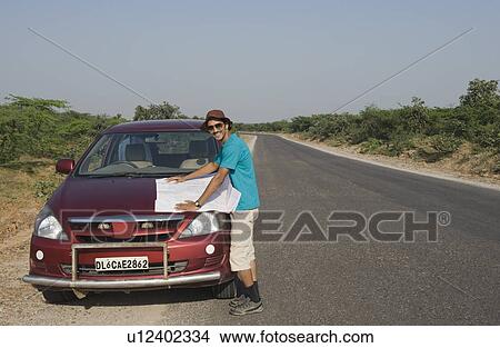 Man with a map on a car hood View Large Photo Image Picture - Man with a map on a car hood. Fotosearch