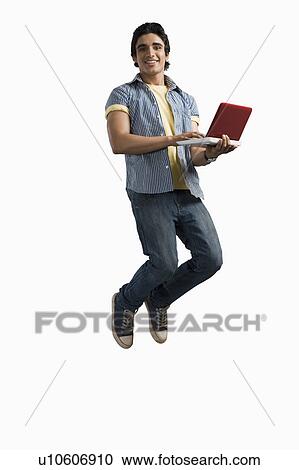 Stock Image - Man working on a laptop and jumping. Fotosearch